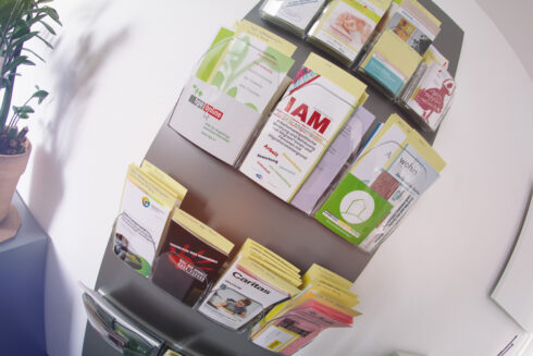 Eine Wand, an der viele verschiedene Flyer und Broschüren in einem Halter befestigt sind.